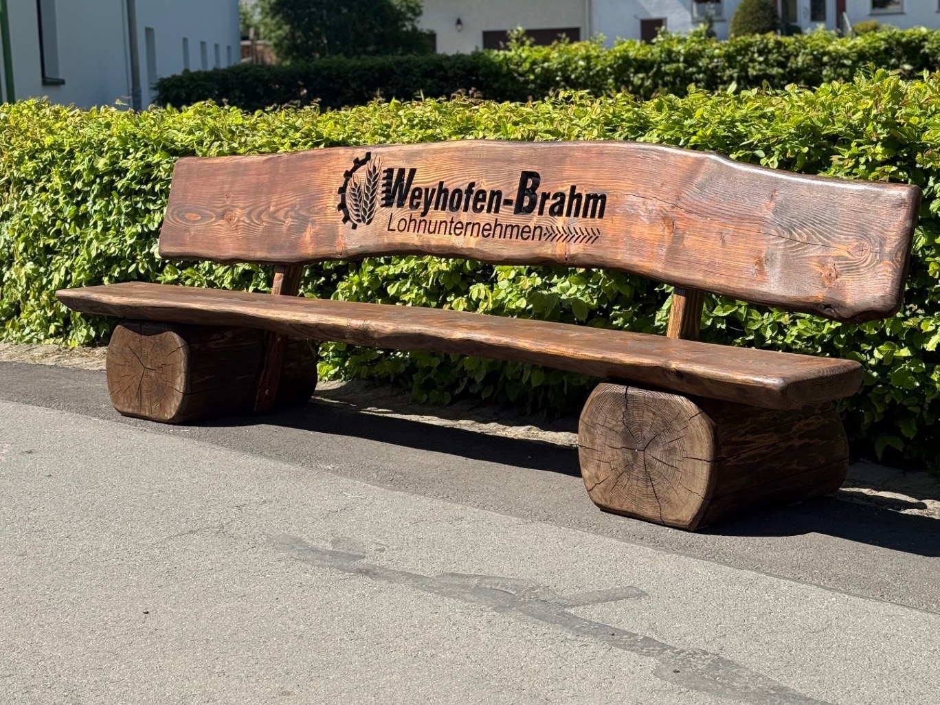 Massive Holzbank aus Douglasie mit tiefer CNC-Gravur des Firmenlogos Weyhofen-Brahm Lohnunternehmen